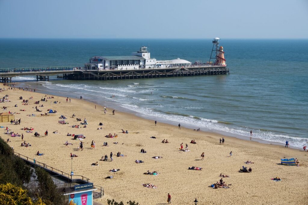 A vibrant summer day at Bournemouth Beach with the iconic pier in the background.