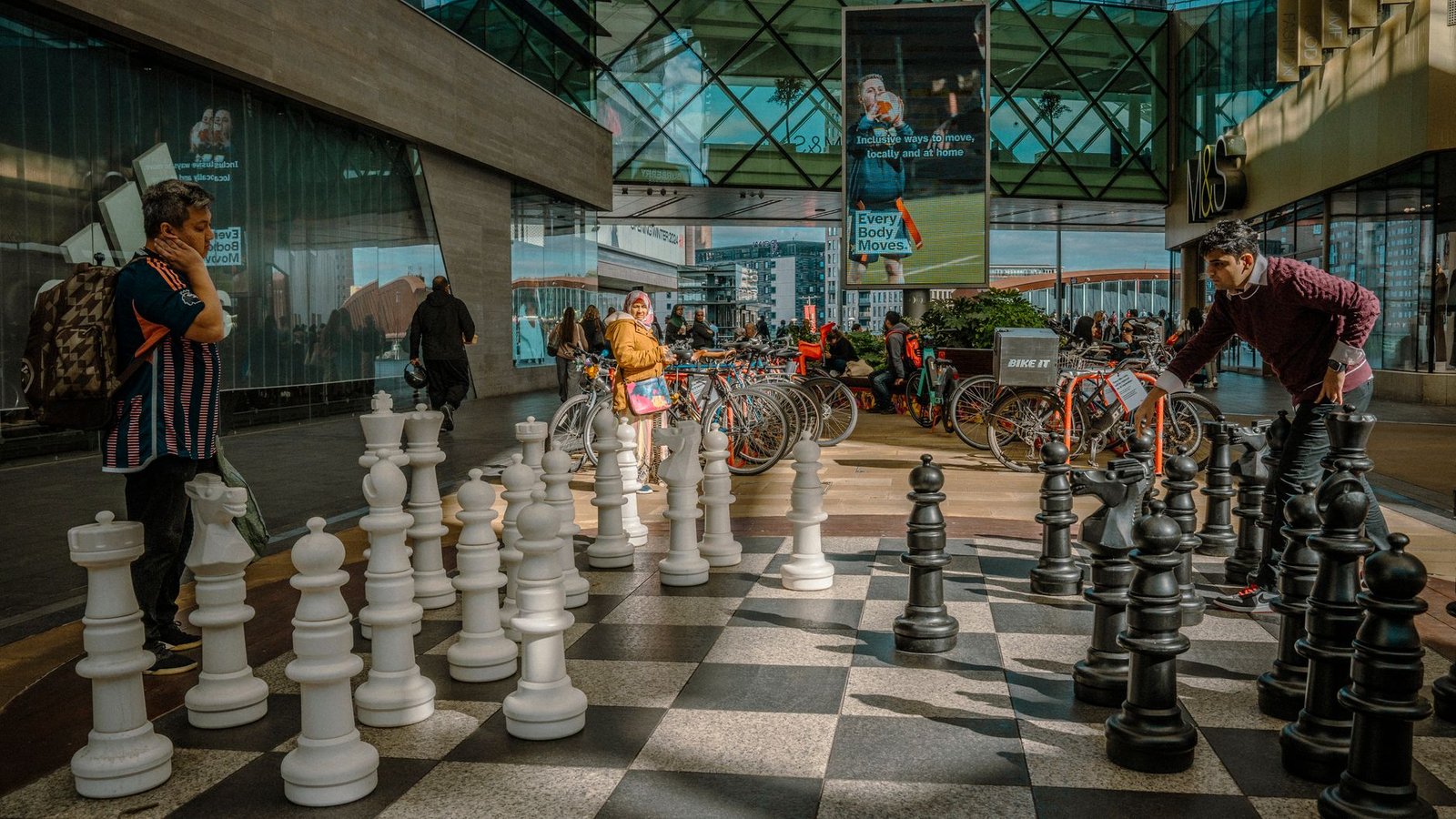 Two people play a giant chess game outside a London shopping center.