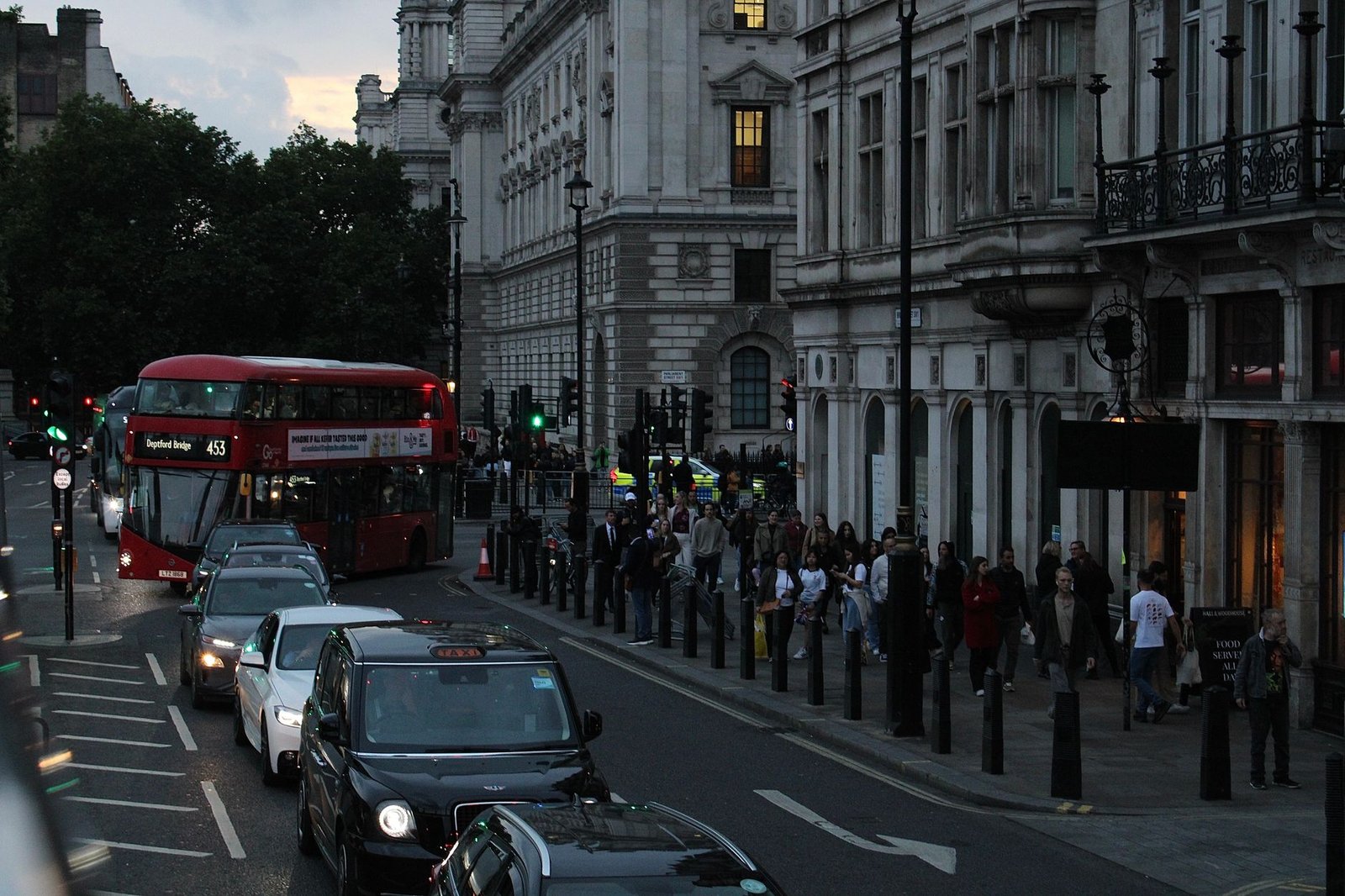 Evening scene of a busy London street with a double-decker bus and pedestrians.