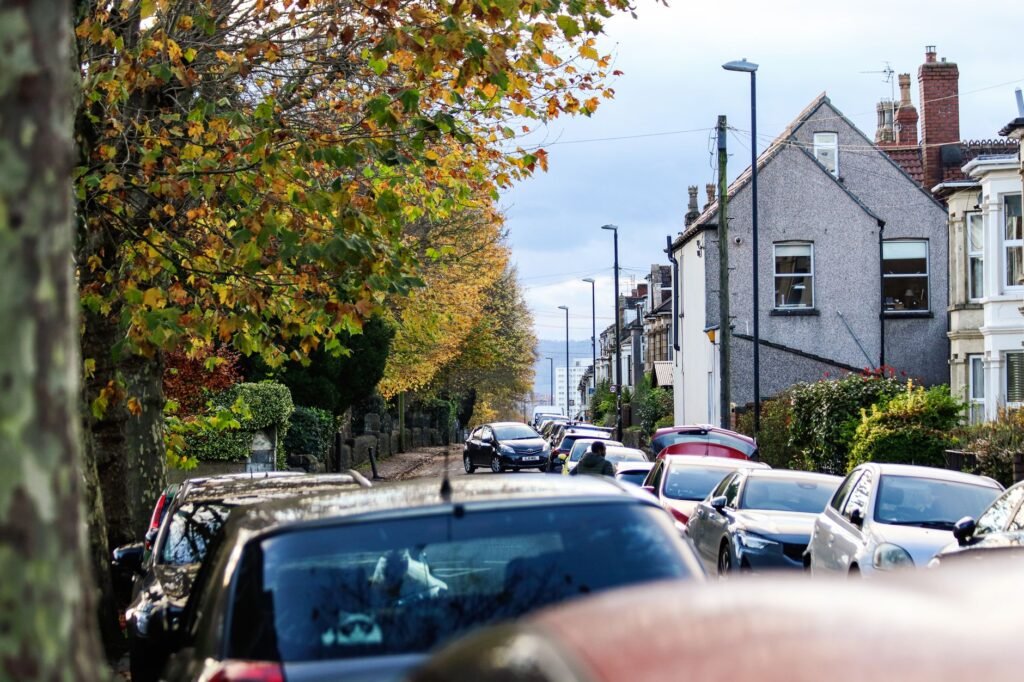 Colorful autumn street scene in Bristol, England showcasing lined cars, houses, and vibrant foliage.