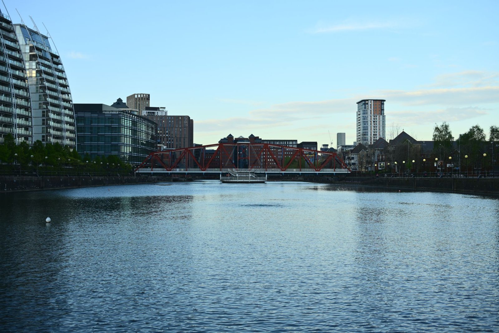 Captivating riverside cityscape featuring a distinctive red bridge at dusk, reflecting urban charm.