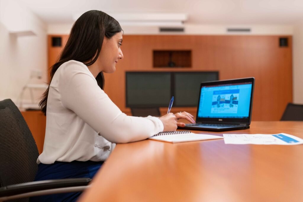 Professional woman working at a laptop in a modern office setting.