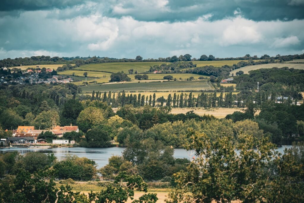 A beautiful countryside landscape near London featuring rolling hills and lush greenery under a dynamic sky.