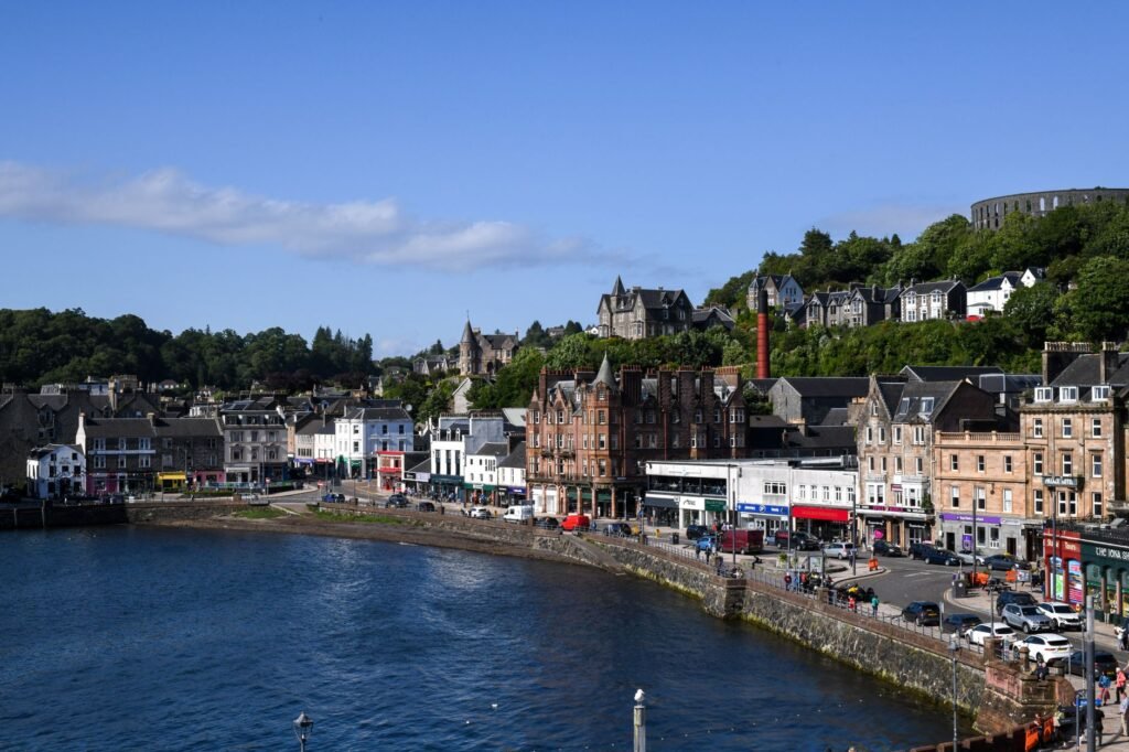 Stunning view of Oban Bay, Scotland, featuring the waterfront and historic buildings under a clear blue sky.