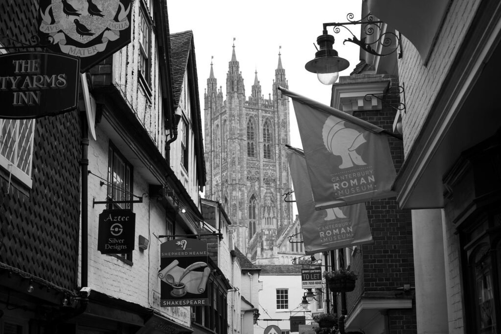 Black and white photograph of Canterbury Cathedral from a historic street in Canterbury, UK.