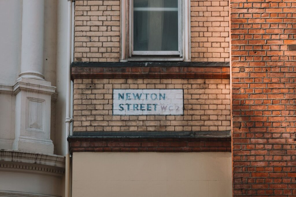 Close-up of Newton Street sign on a brick facade in London, capturing urban architectural details.