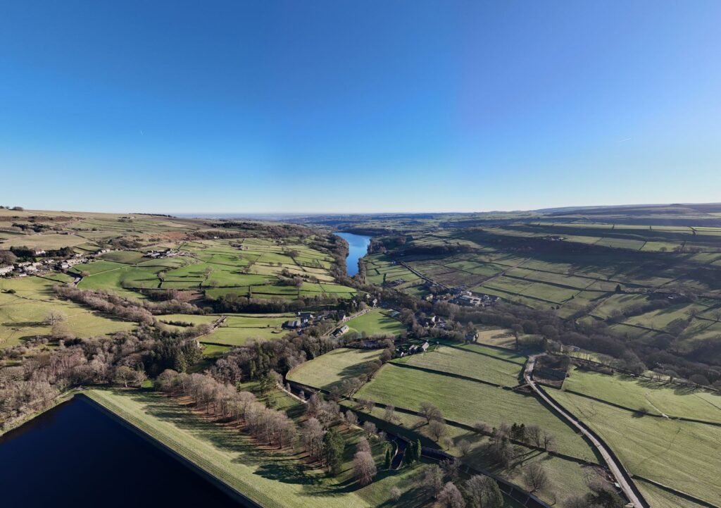 Stunning aerial panorama of green landscapes and river in Peak District National Park.