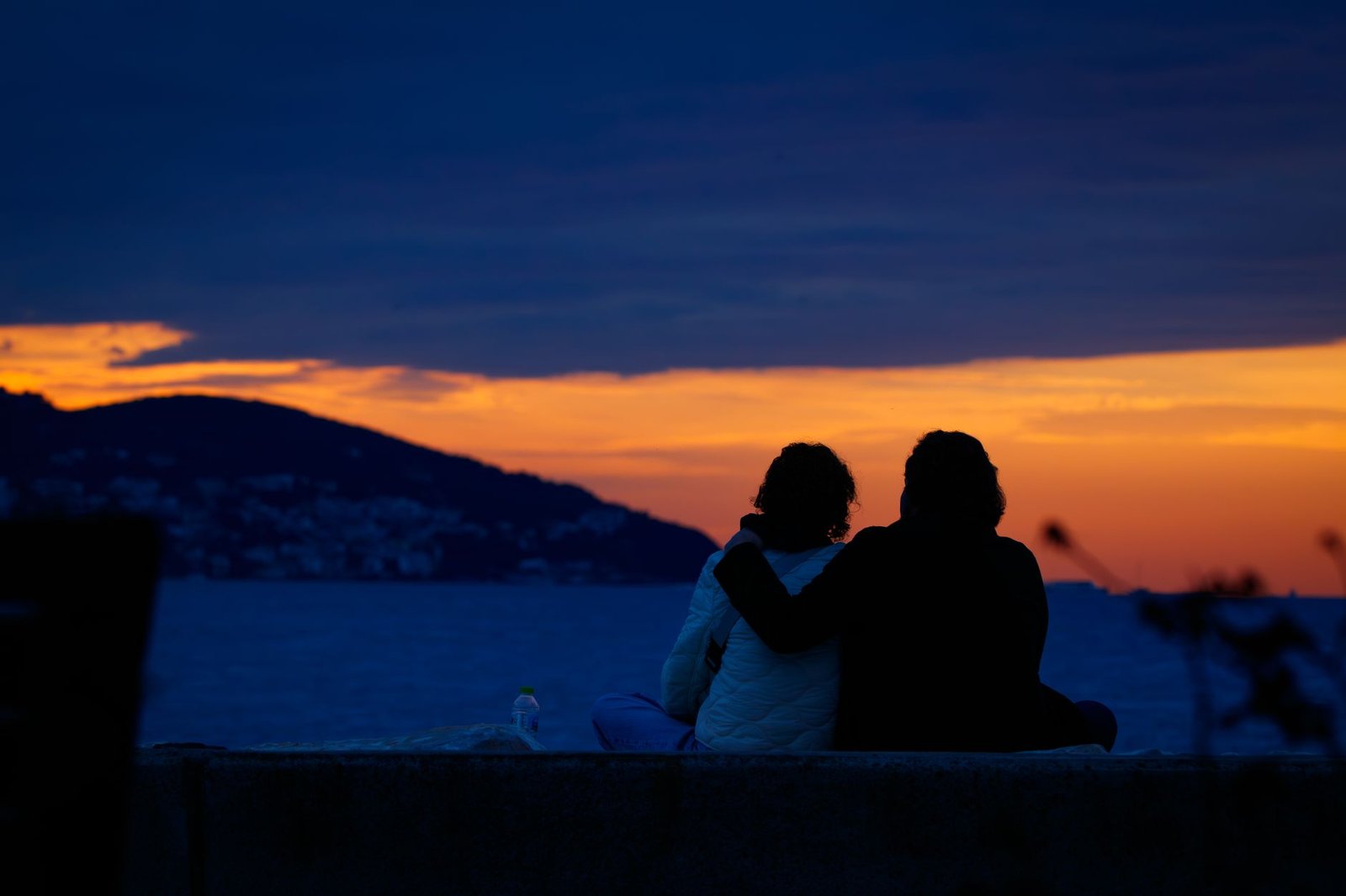 Two adults walking beside Southampton waterfront at night