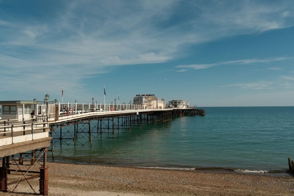 A serene view of Worthing Pier stretching into the calm sea under a bright blue sky.