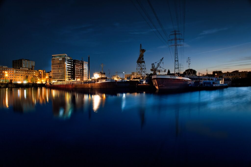 Dramatic nighttime cityscape with illuminated harbor and reflections.