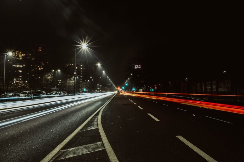 Captivating long exposure of city street at night showing dynamic light trails from vehicles under streetlights.