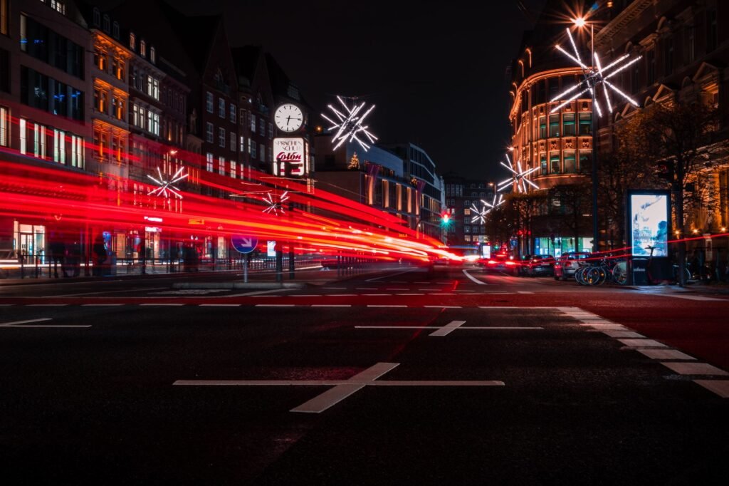 Vibrant long exposure of a bustling Hamburg street at night with colorful lights and festive decorations.