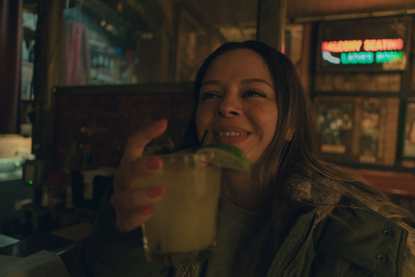 A cheerful woman savoring a cocktail in a cozy San Francisco bar, embracing the night ambiance.