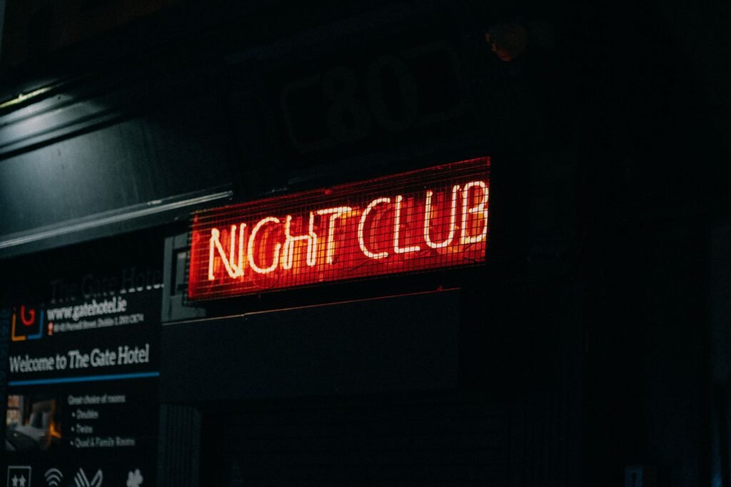 Close-up of a neon-lit 'Night Club' sign in a dark urban setting capturing nightlife ambiance.