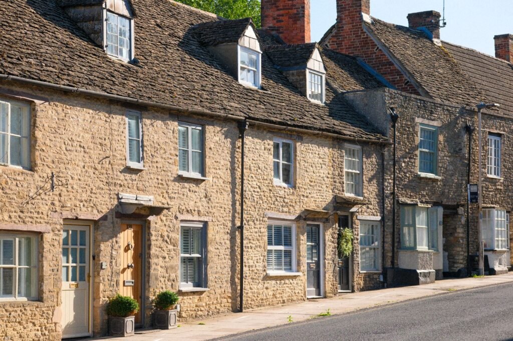 Picturesque stone cottages line a street in Malmesbury, showcasing classic English architecture.