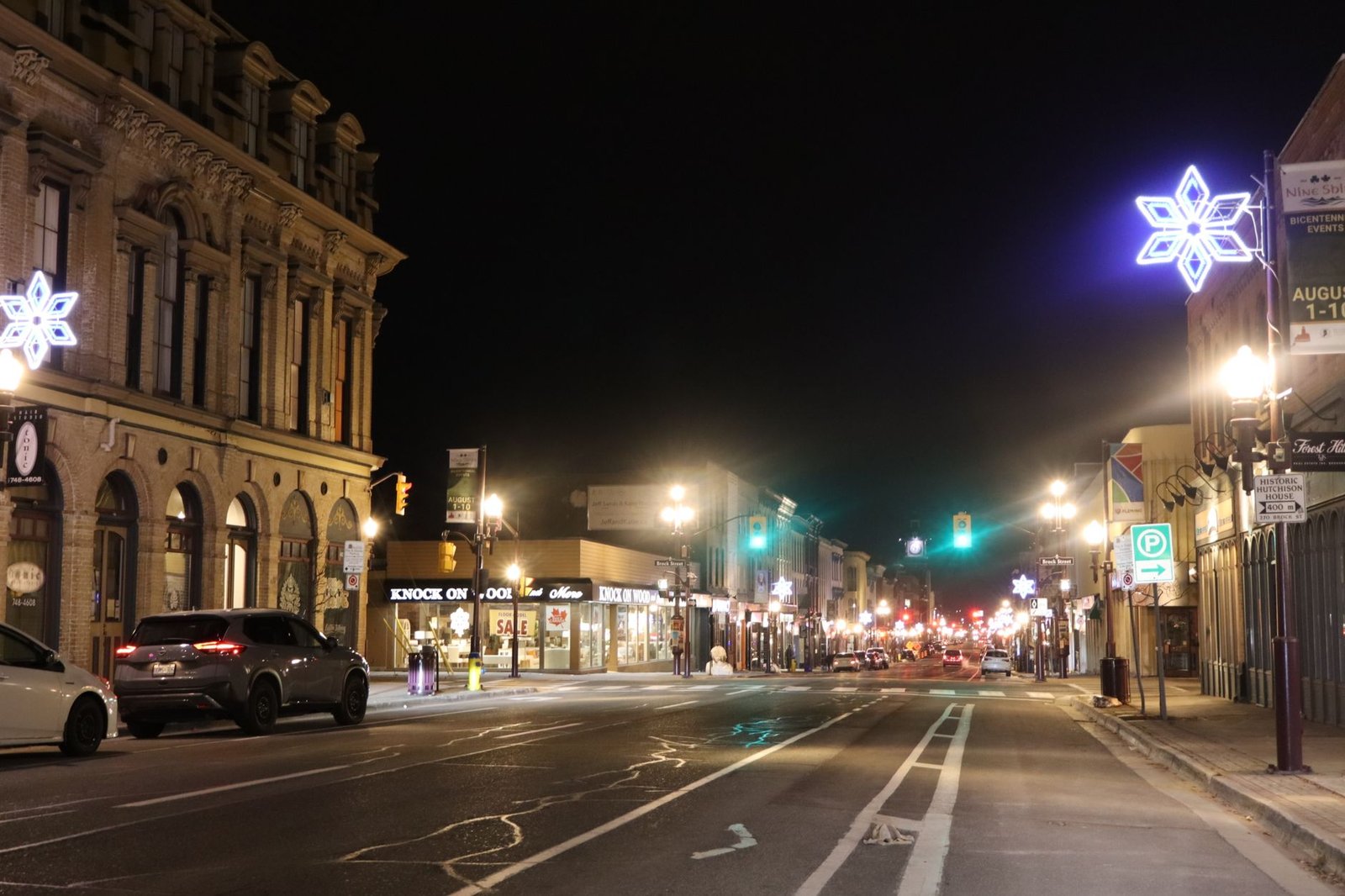 Vibrant night scene on George Street, Peterborough, featuring illuminated storefronts and street decorations.