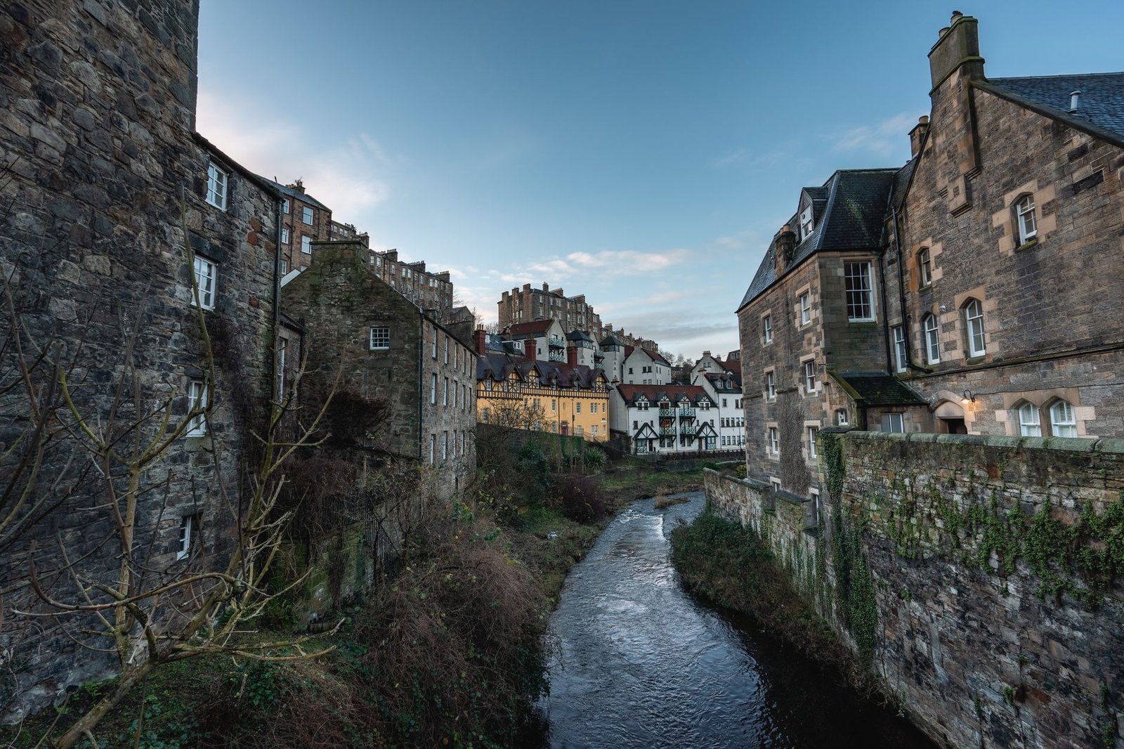 Beautiful view of historic buildings along a river in Edinburgh, Scotland, showcasing gothic architecture.