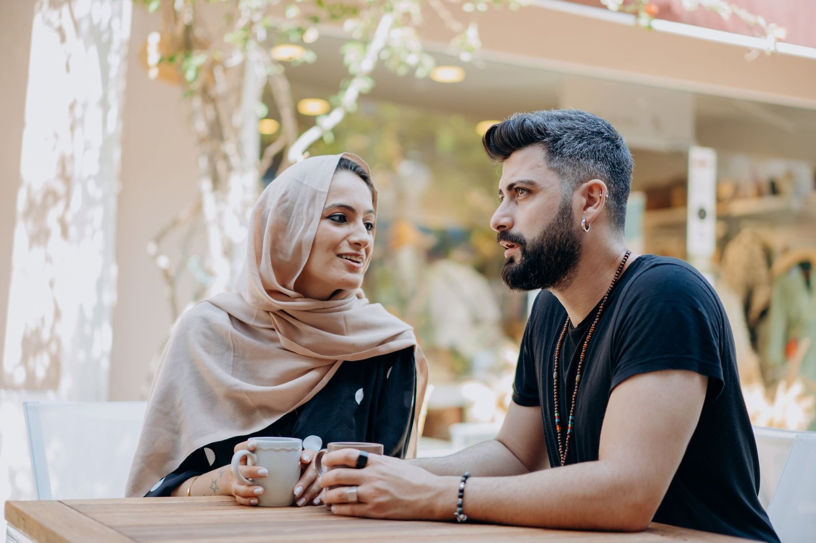 A Muslim couple shares a moment of affection while enjoying coffee outdoors.