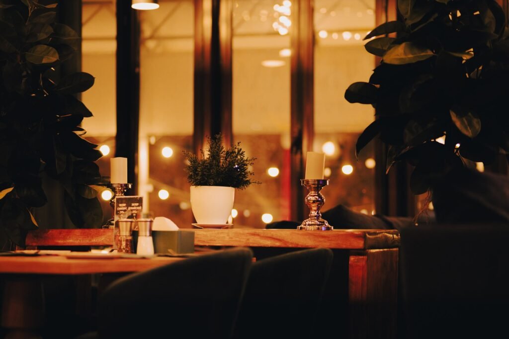 Warm and inviting restaurant table setup with candles and plants, creating a cozy atmosphere.