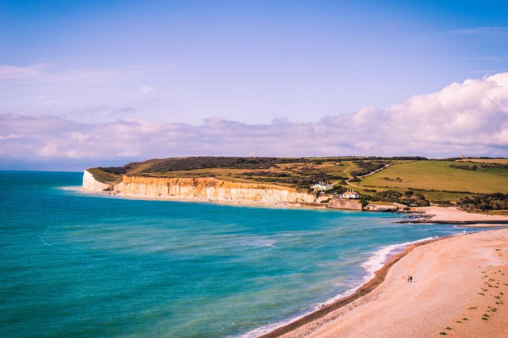 A breathtaking aerial view of Eastbourne's coastline, showcasing cliffs, turquoise waters, and sandy beach under a clear summ