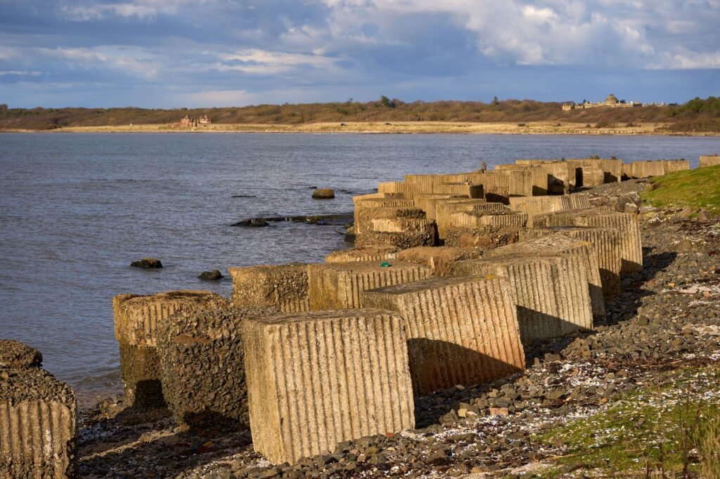 Concrete coastal defenses along the shore of Gosford Bay in East Lothian, Scotland, during spring.