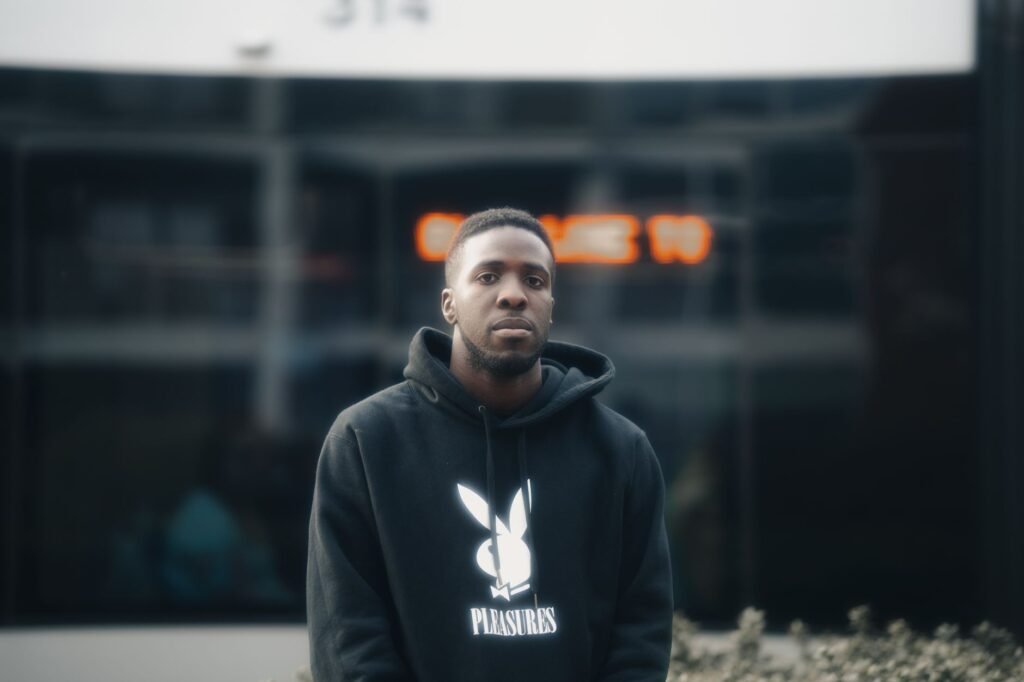 Portrait of a man in a hoodie with urban background, showcasing casual street style.