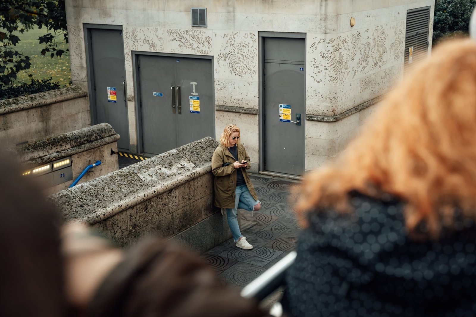 Casual urban scene of woman using phone near stone wall in London.