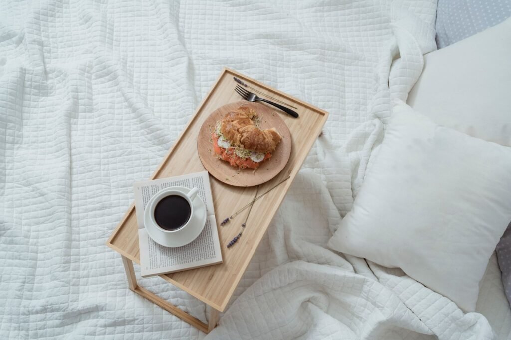 Breakfast in bed with a croissant and coffee on a tray, exuding cozy comfort.