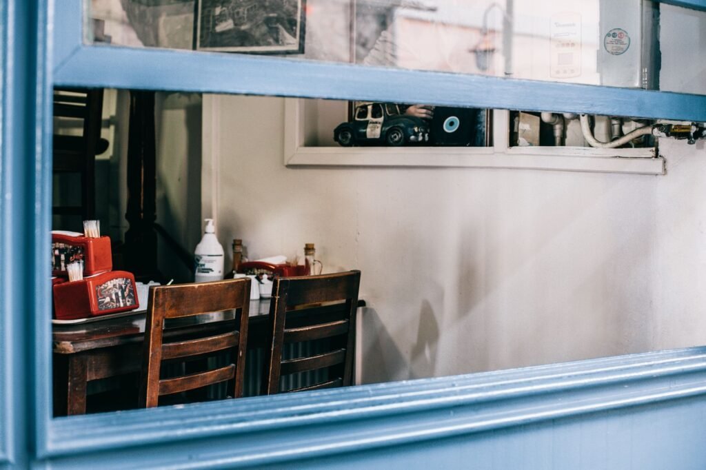 Cozy interior of aged empty cafeteria with wooden chairs and table in bright daylight