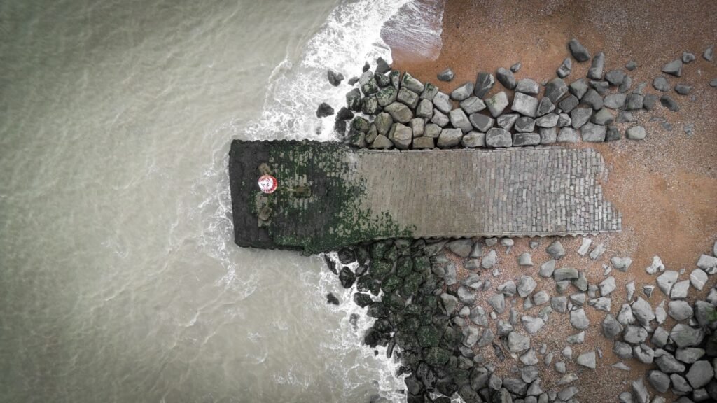 Aerial view of a rock pier meeting the ocean in Eastbourne, UK.