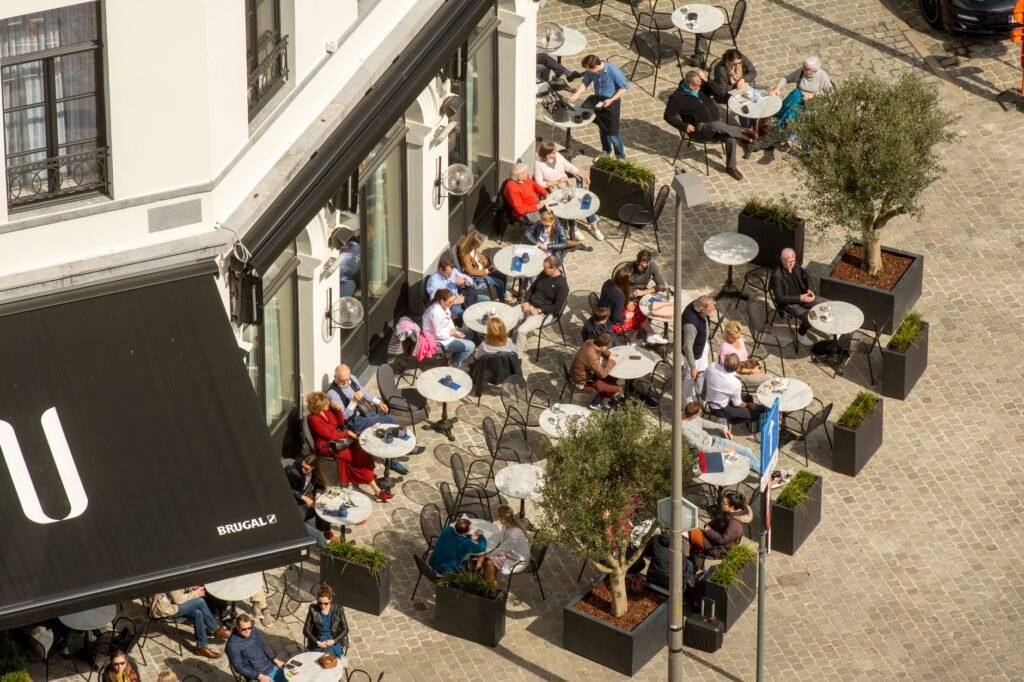Aerial view of people enjoying an outdoor café in a vibrant city setting.