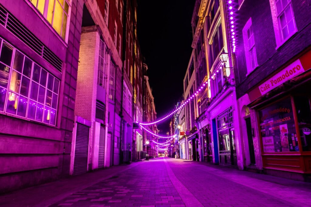 A city street illuminated by vibrant purple neon lights, creating a lively urban atmosphere at night.