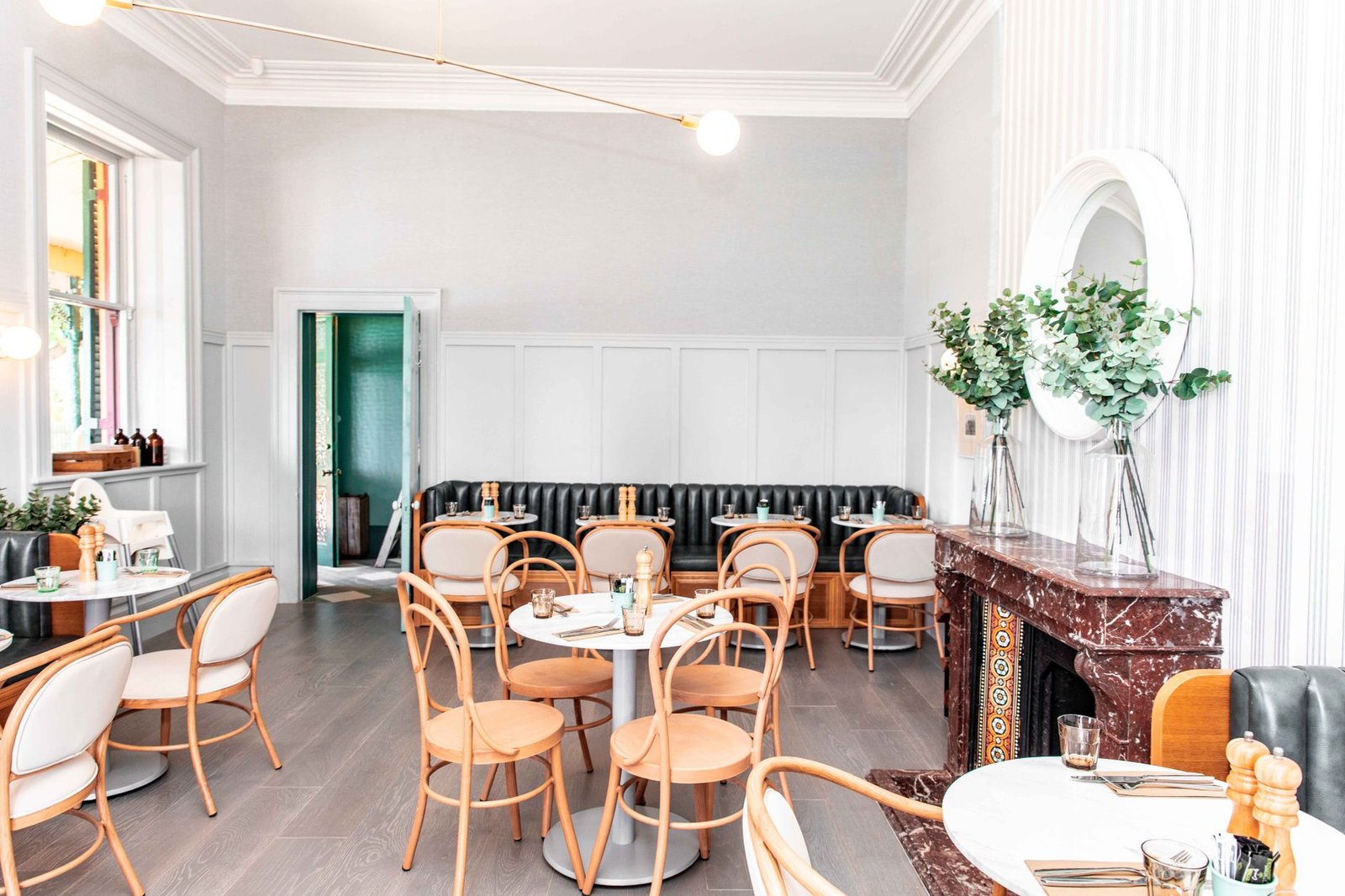 A bright and stylish restaurant interior featuring chic wooden chairs and a sleek table setting.