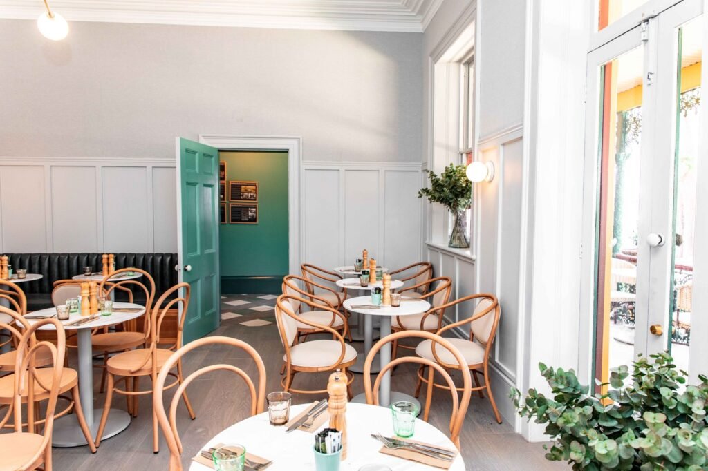Bright and stylish restaurant interior with wooden chairs and white tables, ready for dining.