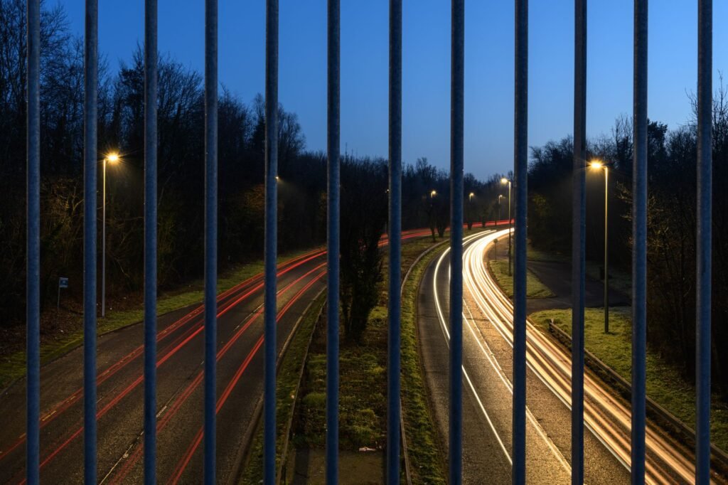 Long exposure of traffic lights through bars, showcasing the dynamic flow of evening traffic in Craigavon.