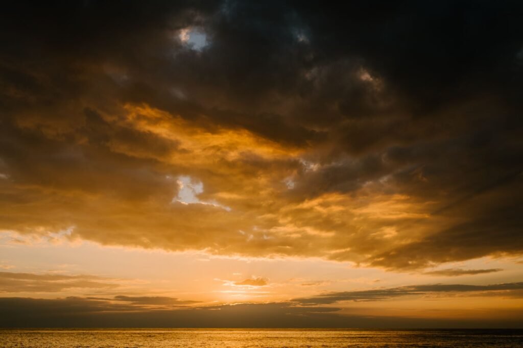 A breathtaking sunset with dramatic clouds over the ocean, capturing the golden hour.