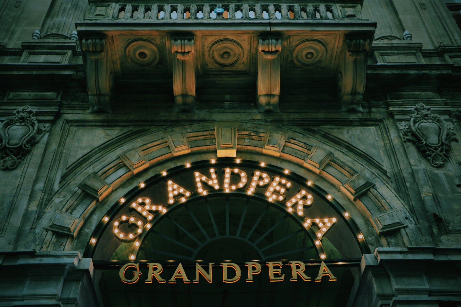 A low angle shot of the Grandpera building facade illuminated at night, showcasing classic architecture.