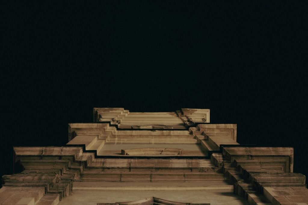 A striking low angle view of an old building facade against a dark night sky, emphasizing architectural details.