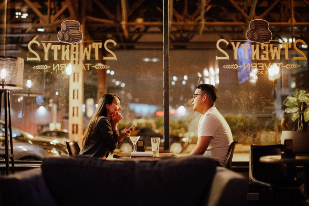 A couple engaged in conversation during an evening at a cozy, urban café.
