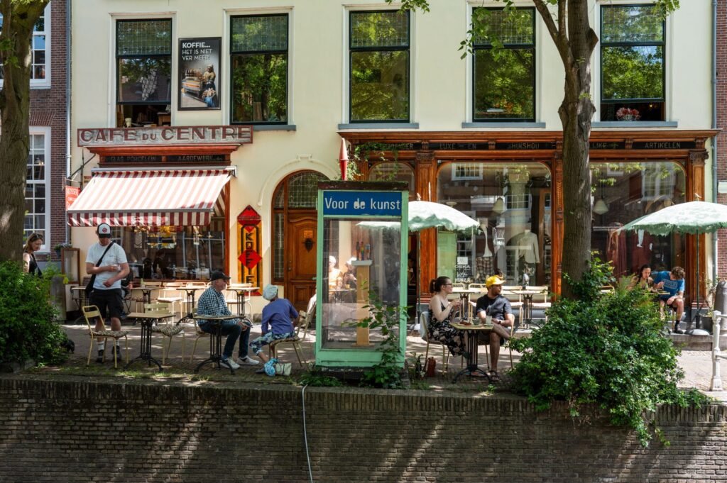 Outdoor cafe scene near canal with people enjoying summer day in European city.
