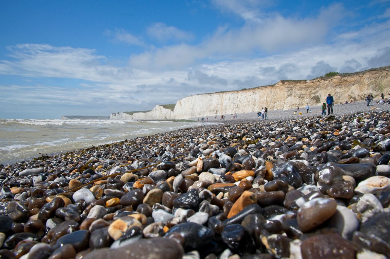 Scenic view of a pebble beach and white cliffs under a blue sky in England.