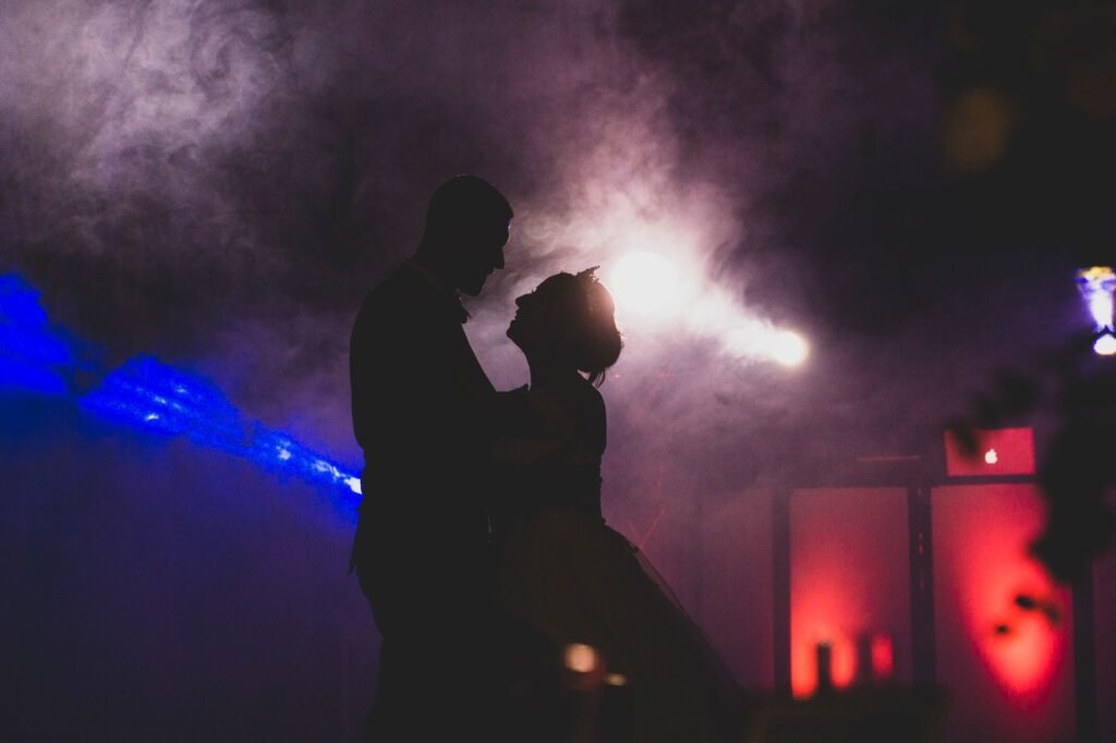 A romantic photo capturing a couple dancing in silhouette with dramatic lighting and smoke effects.