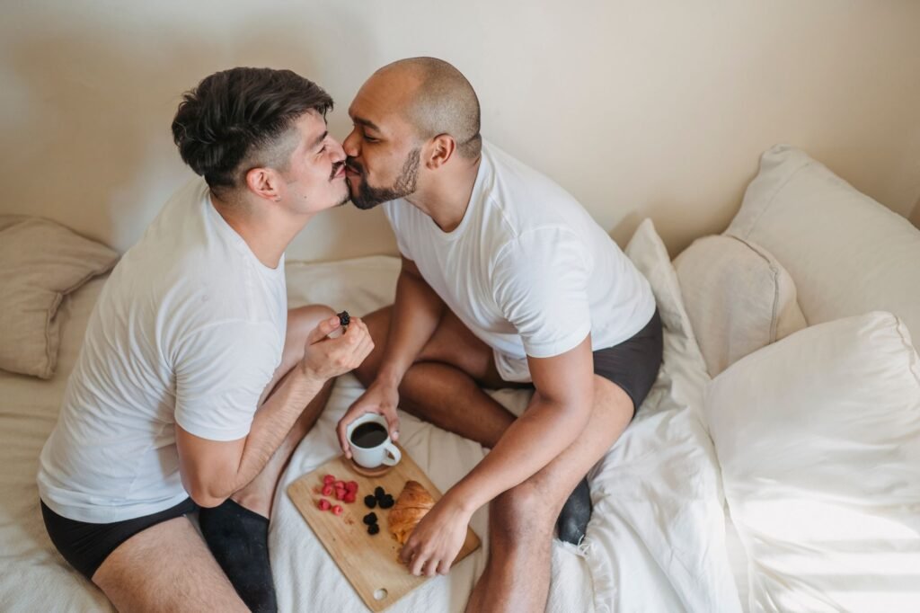 Loving gay couple enjoying breakfast and affection in bed, a perfect blend of romance and comfort.