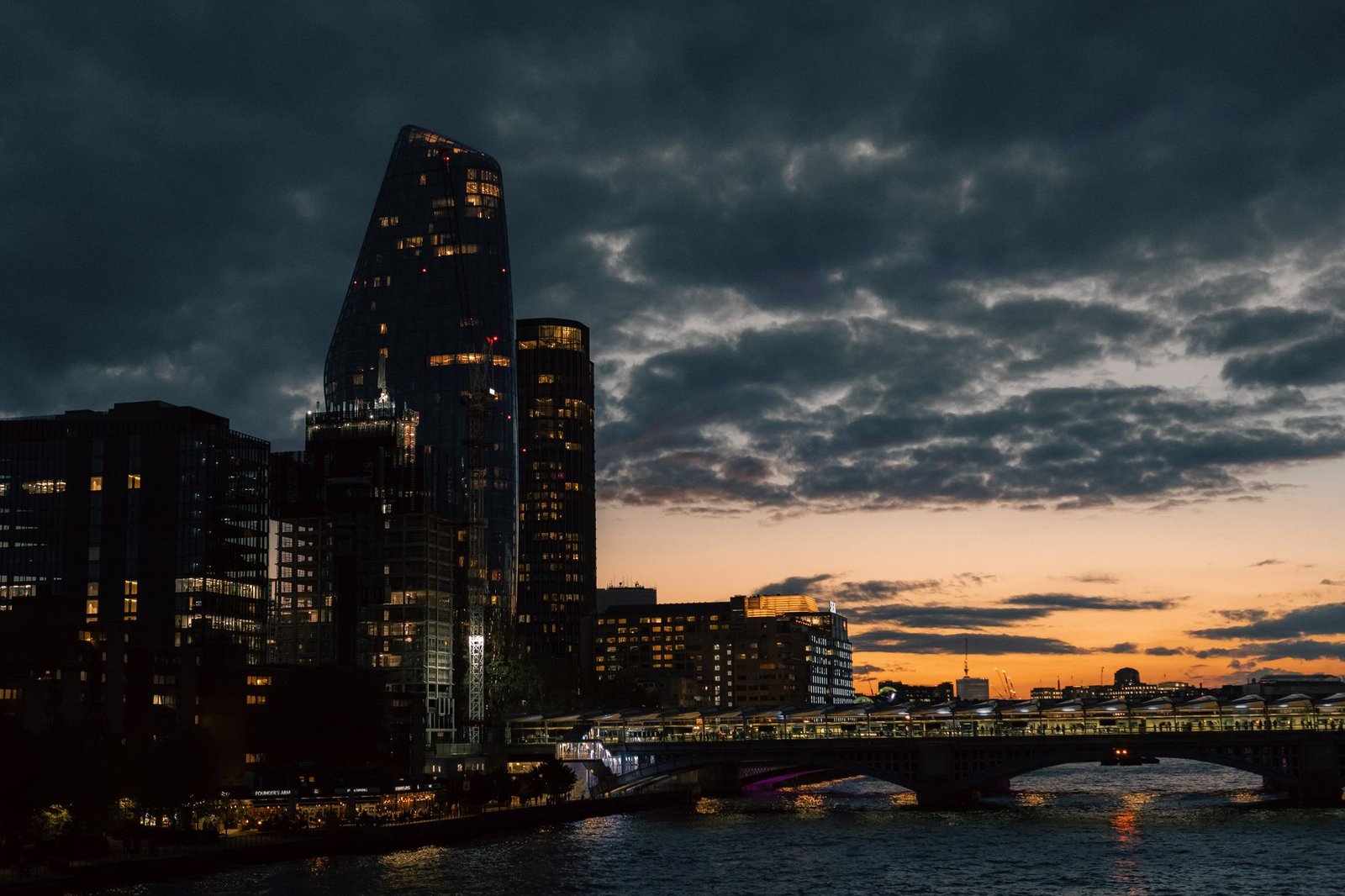 Dramatic view of London's skyline with illuminated buildings at twilight, offering a serene urban landscape.