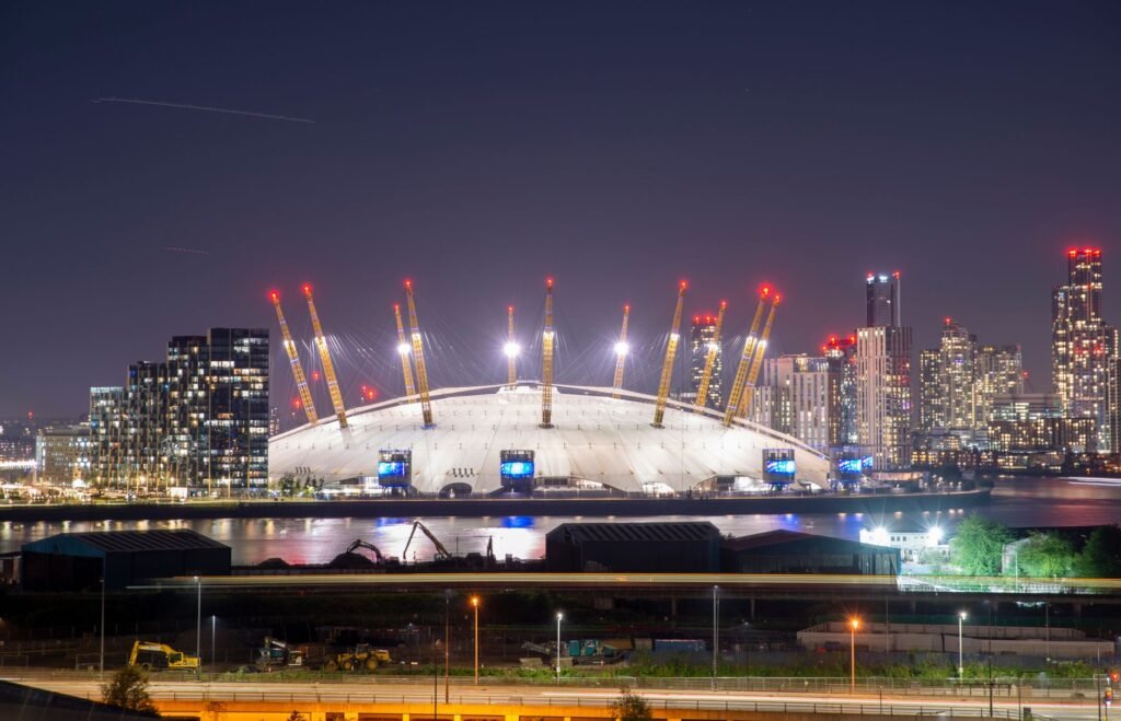Illuminated O2 Arena and London skyline at night showcasing urban architecture.