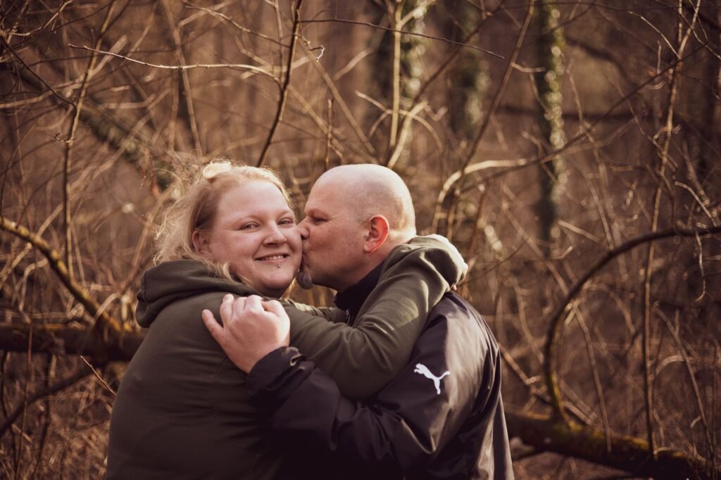 A joyful couple embracing and sharing a tender moment in a scenic forest area.