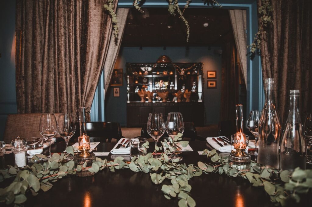 Beautifully decorated dining table with glassware and greenery in a cozy restaurant setting.