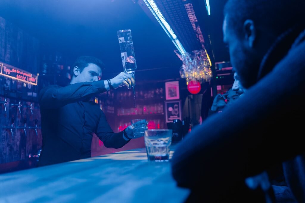 A bartender skillfully pouring drinks in a lively bar setting with patrons.