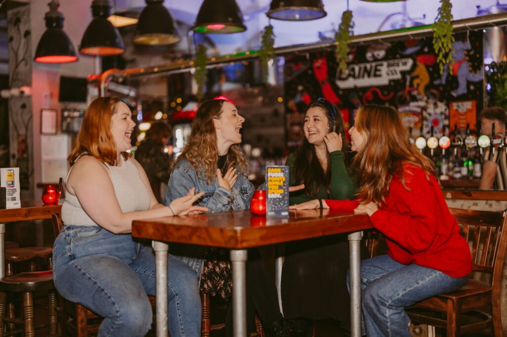 Four women enjoying conversation in a lively Islamabad cafe with colorful decor.