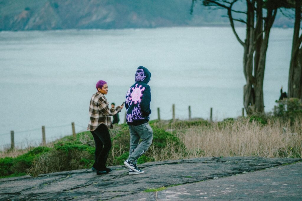 Young adults with colorful fashion walking by the San Francisco coast, enjoying a scenic day outdoors.